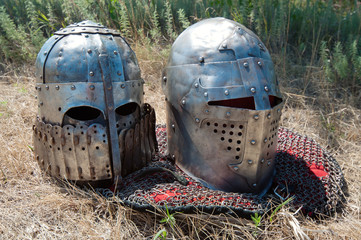 Two medieval knight's helmets on grass, horizontal shot
