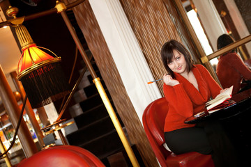 Beautiful young woman with personal organizer in cafe