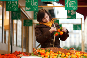 Beautiful young customer selecting tangerines at market
