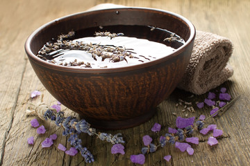 Bowl of water and lavender petals on old wood. Spa treatments