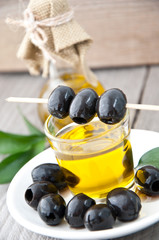 plate with olives and a bottle of olive oil on a wooden backgrou