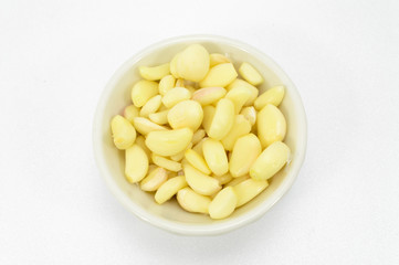 Fresh peeled garlic in a bowl, isolated on white background.