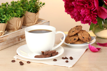 cup of coffee, cookies, chocolate and flowers on table in cafe