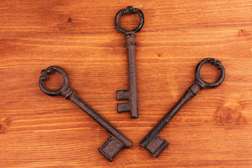 Three antique keys on wooden background