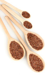 flax seeds in wooden spoons on white background close-up