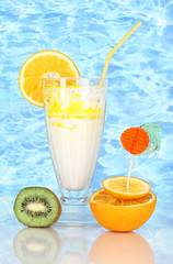 Delicious milk shakes with fruit on blue sea background