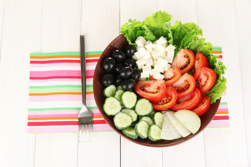 tasty Greek salad on white wooden background