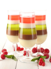 fruit jelly in glasses, berries and mint on wooden table