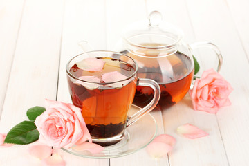 teapot and cup of tea with roses on white wooden table