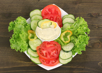 Chopped vegetables and sauce on plate on wooden table
