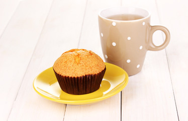 Fresh muffin with tea on wooden background