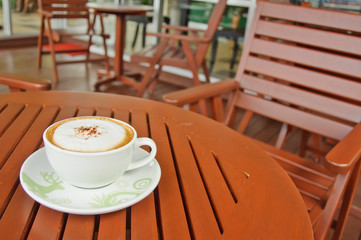 A cup of Capuchino coffee on wooden table