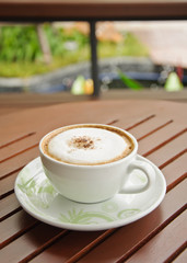 A cup of Capuchino coffee on wooden background.