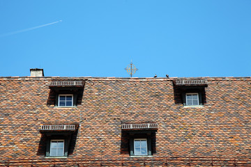 Naklejka premium Roof with shuttered windows on blue sky background
