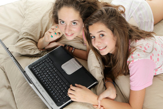Jeunes filles avec ordinateur dans un lit