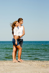 Fototapeta na wymiar Happy young couple standing on windy summer day by the blue sea