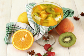 punch in glass with fruits, on white wooden table