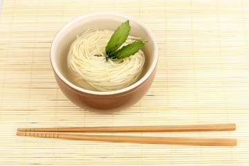 asian noodles in bowl on bamboo mat
