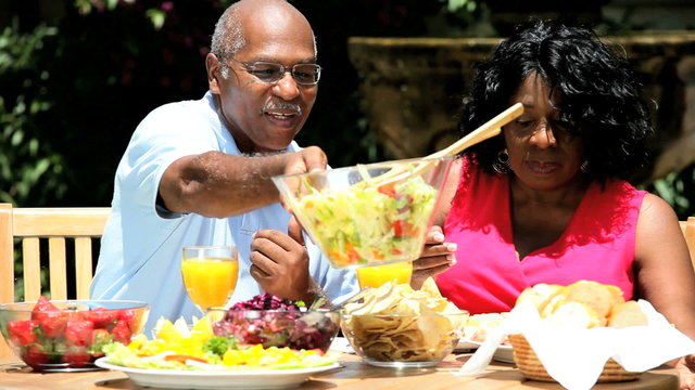 Ethnic Senior Couple Eating Healthy Meal In Garden