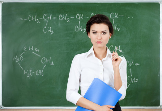 Serious teacher stands at the blackboard