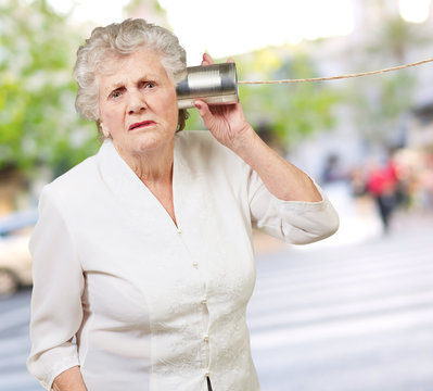 Portrait of a senior woman hearing with metal tin