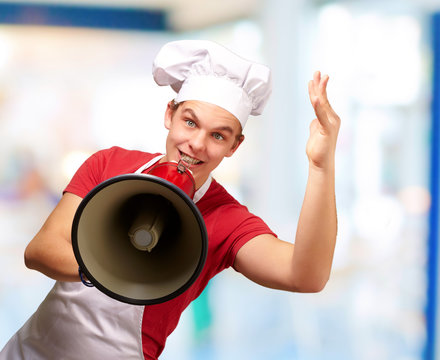 portrait of happy cook man shouting using megaphone indoor