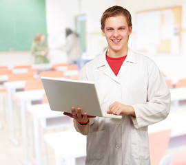 portrait of young student holding laptop at classroom