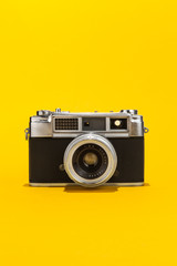 Retro analog film camera on yellow background