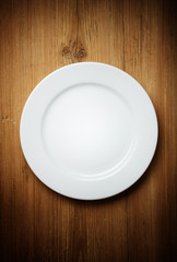 Empty white plate on wooden table