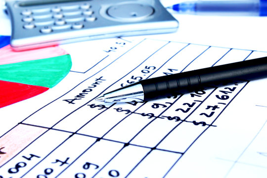 pen placed over financial statistics and charts