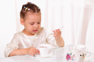 Attractive little girl drinking cup of tea