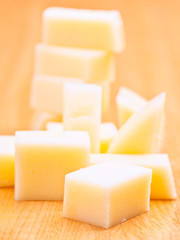 cheddar cheese cut into cubes, on wooden base