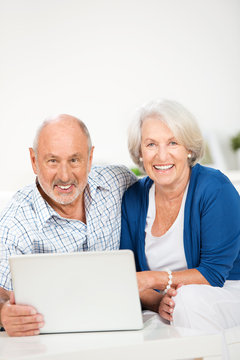 lachendes älteres ehepaar am laptop
