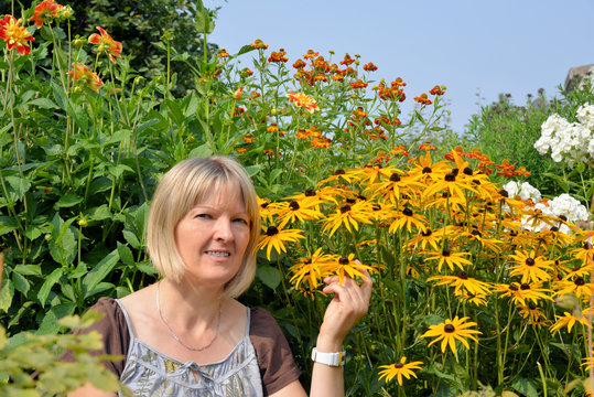 Frau mit Sommerblumen im Garten
