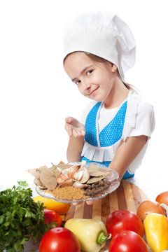 Happy little chef cook offers a plate with spices