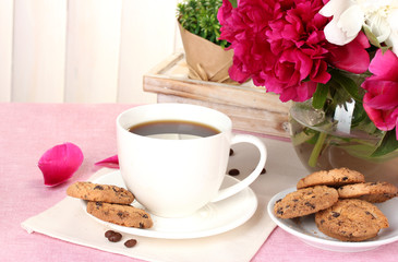 cup of coffee, cookies and flowers on table in cafe