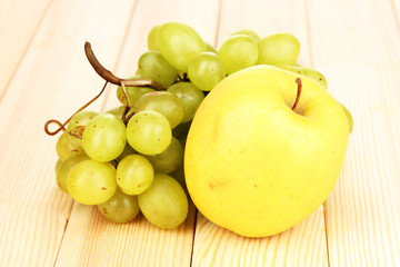 ripe sweet grapes and apple on wooden background
