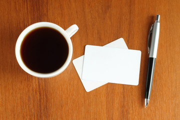 Cup of coffee with business cards and pen