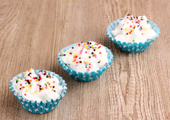 Creamy cupcakes on wooden background