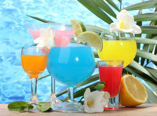 exotic cocktails and flowers on table on blue sea background