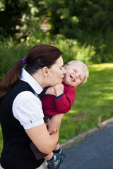 Young mother and her toddler boy hugging summer park