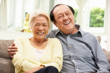 Senior Chinese Couple Relaxing On Sofa At Home