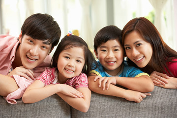 Chinese Family Sitting And Relaxing On Sofa Together At Home