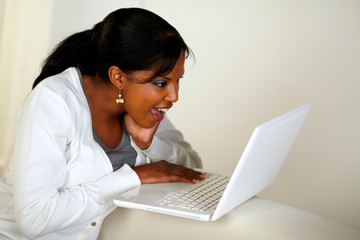 Surprised young woman reading a message on laptop
