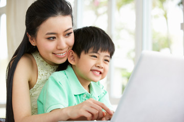 Fototapeta premium Chinese Mother And Son Sitting At Desk Using Laptop At Home