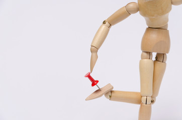 Wood figure with a red pin stuck in his foot.