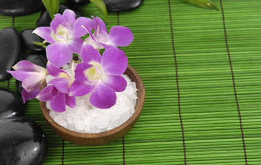 herbal salt in bowl with orchid and stones on green mat