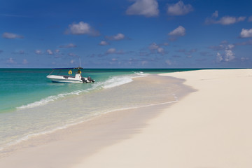 Fototapeta na wymiar Tropikalne Piaszczysta plaża w słoneczny dzień z łodzi w tle