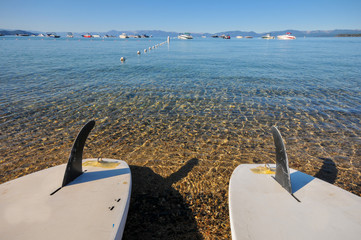 Two paddle boards on shore of lake