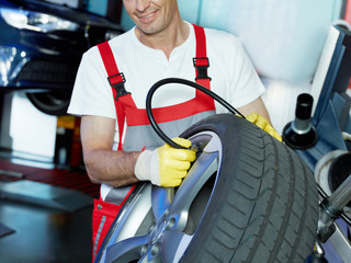 Master mechanic in a garage is checking tyre pressure